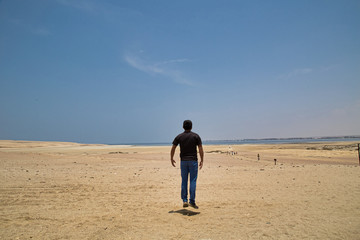 young man on sand in a desert near Huacachina, Ica region, Peru. The sunset desert view