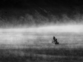 People on the boat on an empty sea surrounded by fog