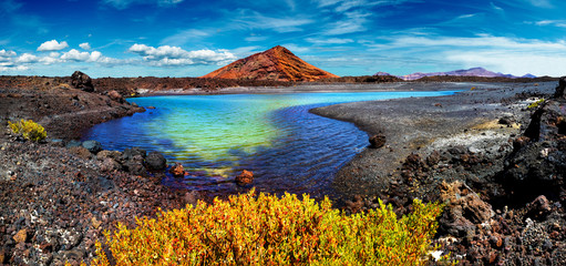 Beeindruckende und malerische vulkanische Natur, einzigartig im Timanfaya-Nationalpark. Roter Berg und grüne Pfütze in der Nähe der Meeresküste auf der Kanarischen Insel Lanzarote