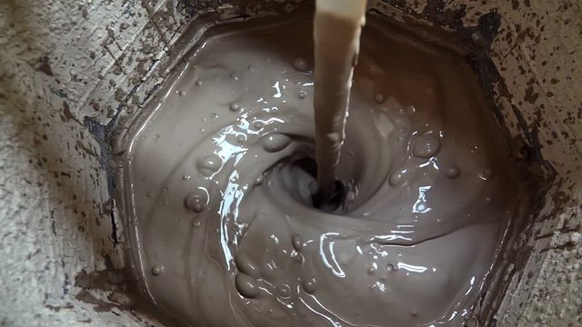Mixing ceramic or cement.This stock video shows a close-up shot of a machine mixing ceramic or cement in a boiler.