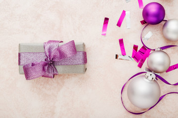 Christmas or New Year composition. Xmas purple and silver decorations: ribbons and balls on pink pastel background. Flat lay, top view, copy space, frame.