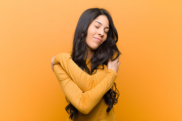 young pretty hispanic woman feeling in love, smiling, cuddling and hugging self, staying single,...