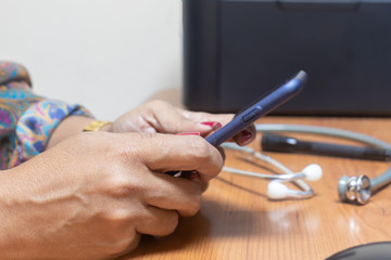 Female, hispanic ethnicity, medical doctor hands with pen ready to write, Sitting at the work place. Pediatrician, neonatologist, cel phone & small size stethoscope for premature patient in background