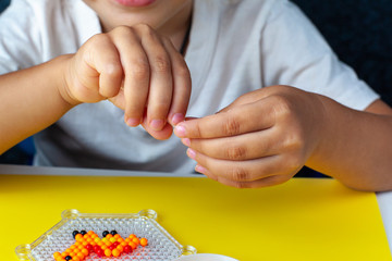 Aqua mosaic. A child collects a dinosaur toy. Hands close up.