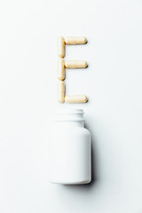 Vitamin E. The letter E from yellow pills on a white background. Minimalistic medical concept. View from above.