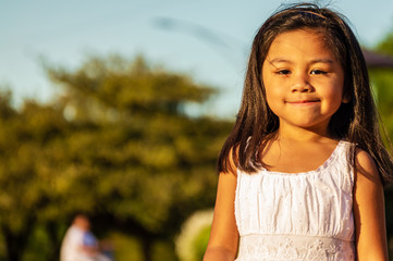 Cute Mexican American girl child is playing in a park in the city.	