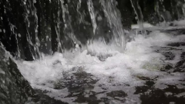 closeup of water falling on rocks in a Japanese garden