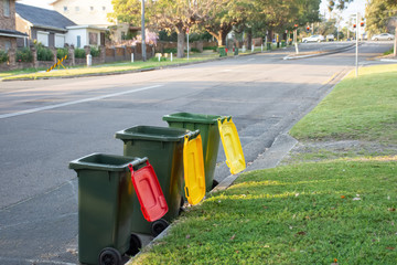 Australian garbage wheelie bins with colourful lids for recycling and general household waste lined...