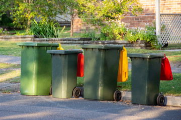 Australian garbage wheelie bins with colourful lids for recycling and general household waste lined...