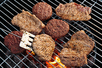 Barbecue grill. A man fries meat steaks and meatballs for hamburgers, turns the meat over with tongs.