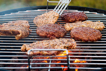 Barbecue grill. A man fries meat steaks and meatballs for hamburgers, turns the meat over with tongs.