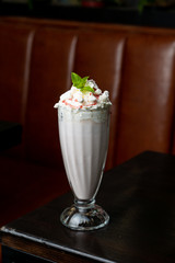 Classic american vanilla milkshake with whipped cream in a retro cafe