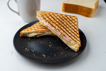 Simple breakfast with grilled  cheese and ham sandwich with melted cheese and coffee