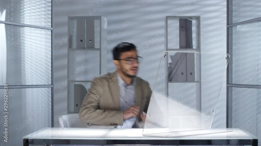 Poster young middle eastern businessman sitting at desk in modern office and start working on futuristic co