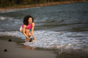 Young woman of mixed race stands in the waves on the surf line on the sea beach.
