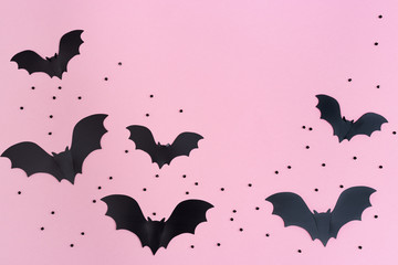 Flat lay with Black bats for halloween party. Paper decorations on pink background for holiday card...