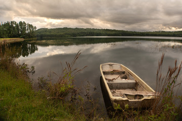 Fototapeta premium paisaje de lago, con un bote anclado durante un atardecer nublado en la naturaleza
