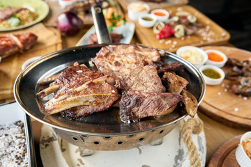 Various grilled meat set heated on coals. Barbecue restaurant menu. Many different food on the table. Dinner party or Banquet