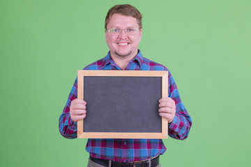 Happy overweight bearded hipster man holding blackboard