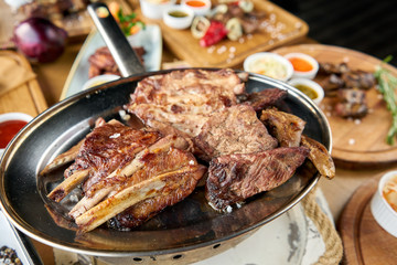 Various grilled meat set heated on coals. Barbecue restaurant menu. Many different food on the table. Dinner party or Banquet