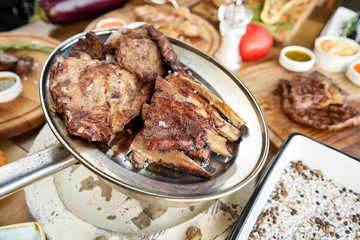 Various grilled meat set heated on coals. Barbecue restaurant menu. Many different food on the table. Dinner party or Banquet
