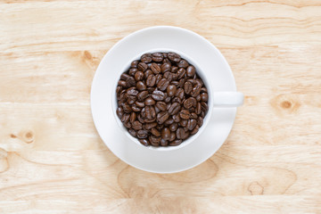coffee beans in white coffee mugs on the wooden background .