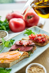 Bruschetta with beef, tomatoes and salmon.. Variety of dishes on the table. Various snacks and antipasti on the table. Restaurant menu. Italian cuisine