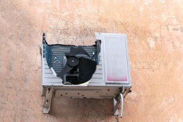 An overworked air conditioner breaks down the blades and body. Traces of damage on the wall.