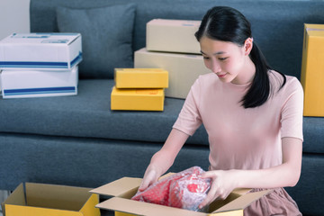 Attractive young teenage entrepreneur preparing parcel box of product for deliver to customer. Young entrepreneur,online sales, or ecommerce concept.