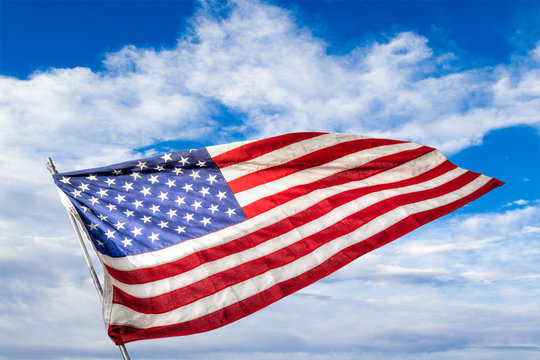 USA Flag Waving Against Blue Cloudy Sky Background With Copy Space