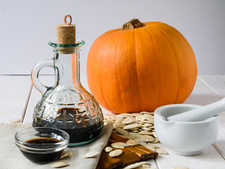 pumpkin oil with pumpkin and pumpkin seeds on a light wooden background