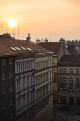 View of the roofs of historic buildings with red tiles during a bright sunset in Prague, Czech Republic.