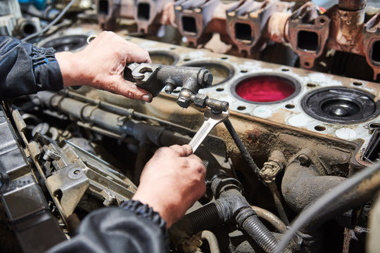 diesel truck engine repair service. Automobile mechanic tightening using wrench
