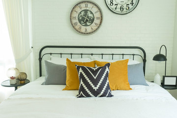 Modern and stylish of a cozy bedroom with yellow, blue, and grey pillow on bed 