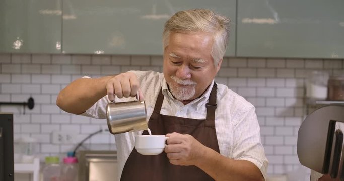 Senior barista making latte art at a coffee shop.