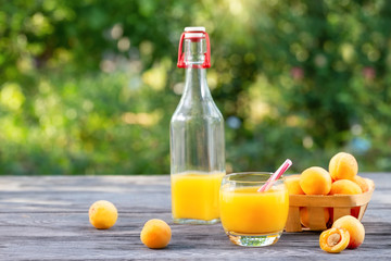 Apricot juice and apricots in basket on wooden table