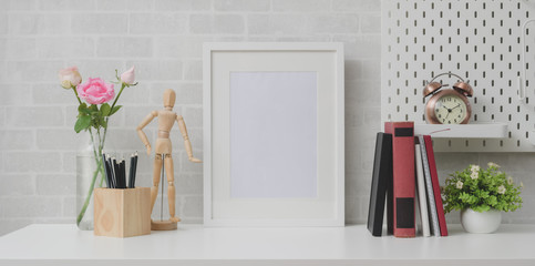 Fototapeta na wymiar Minimal workplace with mock up frame, books and decorations on white table and grey brick wall