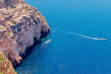 Blue Grotto in Malta. Pleasure boat with tourists runs. Natural arch window in rock