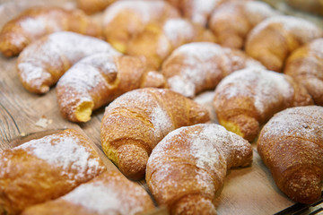 many of croissants. Hot pastries lie on the showcase in the cafe. Buns and bagels in the store.