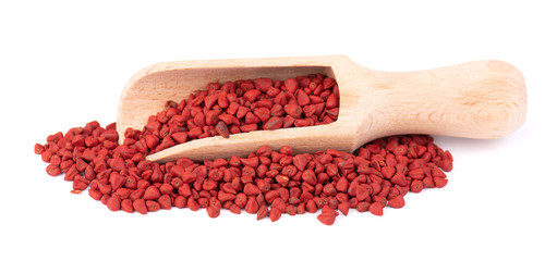 Annatto seeds, in the wooden spoon, isolated on white background. Achiote seeds, bixa orellana....