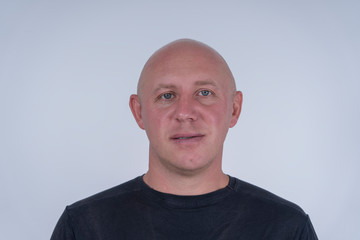 Portrait of middle-aged caucasian bald man looking straight at camera, close up