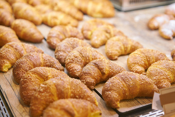 many of croissants. Hot pastries lie on the showcase in the cafe. Buns and bagels in the store.