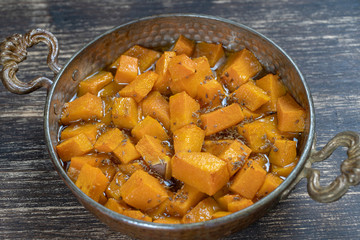 Baked yellow pumpkin with honey, anise, olive oil and spices on a plate on the wooden table. Vegetarian food. Closeup