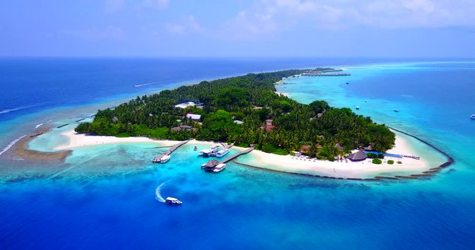 Aerial shot forward motion toward the tropical islands in Oceania. Yacht departing from the wooden dock. Island surrounded with wave beakers. Asure clean sea around the island.