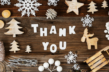 White Letters Building The Word Thank You. Wooden Christmas Decoration Like Sled, Tree And Star. Brown Wooden Background