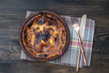 Sweet cottage cheese casserole with raisins and semolina on wooden table. Ceramic bowl with baked cottage cheese casserole , closeup, top view