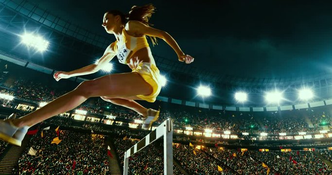 Track and field female runner hurdles on the professional sports arena with bleaches full of people. Athlete wears unbranded clothes. Arena and people on it are made in 3D.