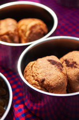 Crispy baked butter cookies in small containers on colourful table cloth