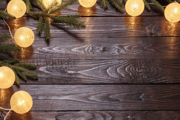 Christmas  lights with fir branchs on dark wooden background