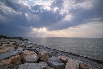 Fototapeta na wymiar Beautiful amazing magnificent scenery of a rocky shore, sea and cloudy moody sky with sunbeams